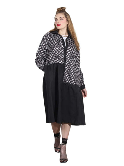 Woman wearing a black and white patterned coat over a black dress.