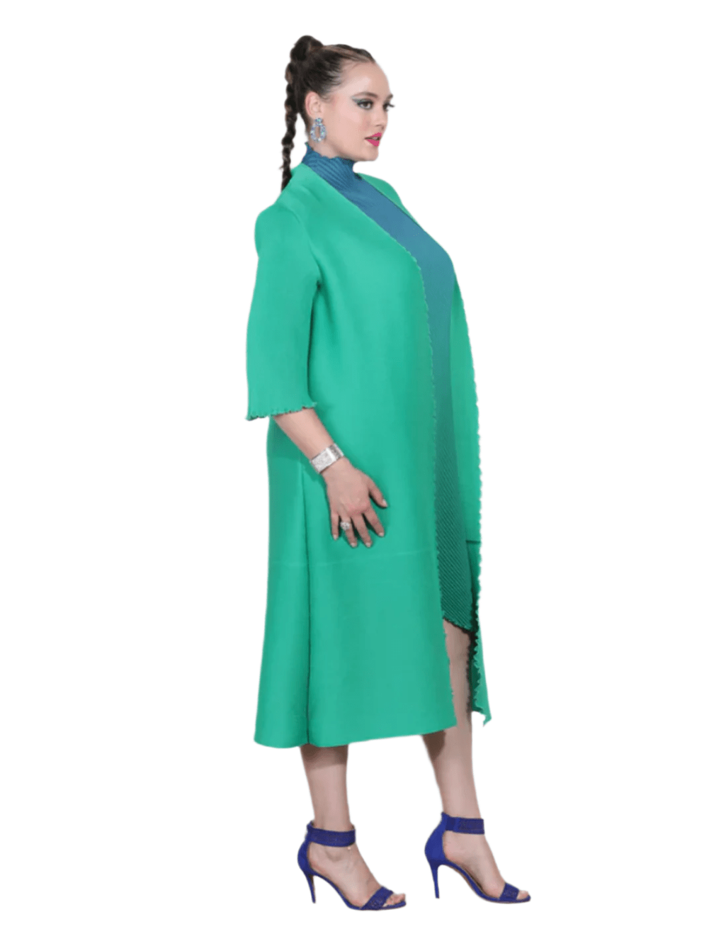 Woman wearing a green dress with a blue top against a white wall.